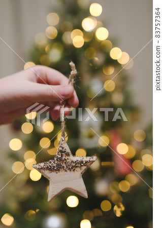 Decorating Christmas tree, holding Christmas toy in a hand. Holiday, Christmas and New Year family celebration concept 83757364