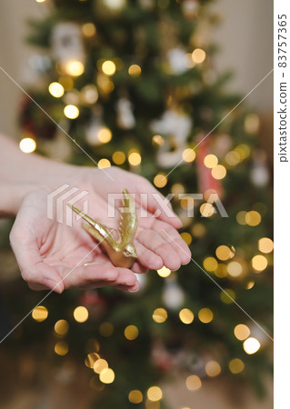 Decorating Christmas tree, holding Christmas toy in a hand. Holiday, Christmas and New Year family celebration concept 83757365