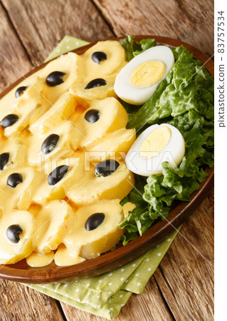 Papa a la Huancaina Huancayo Style Potatoes with boiled eggs close up in the plate. Vertical 83757534