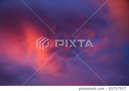 Unusual pink-purple mammatus clouds at sunset. Blurred image for backgrounds. Unusual pink-purple mammatus clouds at sunset. Blurred image for backgrounds. 83757557