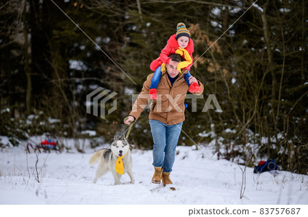 Winter walk, father with daughter and dog in the woods, bright winter clothes. 83757687
