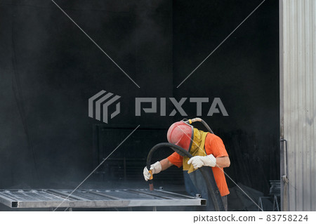 Worker using sandblaster for cleaning surface of metal  83758224