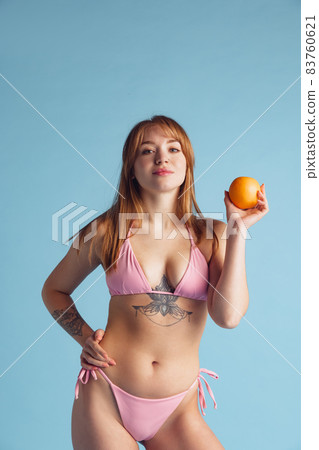 Portrait of young beautiful red-headed woman in inner wear posing isolated over blue studio background. Natural beauty concept. Portrait of young beautiful red-headed woman in inner wear posing isolated over blue studio background. Natural beauty concept. 83760621