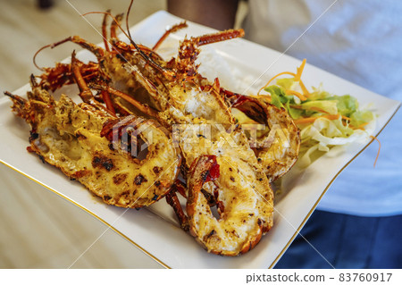 Closeup of freshly grilled lobster tails served with vegetables salad and rise. Closeup of freshly grilled lobster tails served with vegetables salad and rise. 83760917
