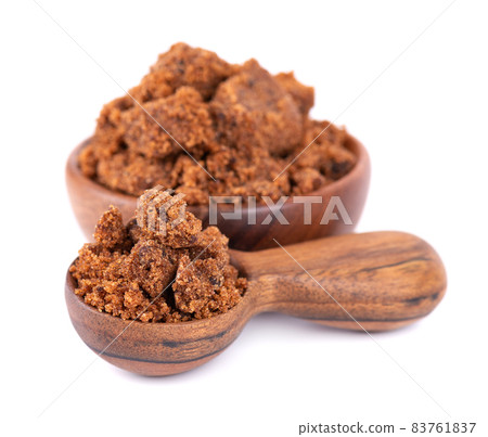 Muscovado sugar in wooden bowl and spoon, isolated on white background. Barbados sugar, khandsari or khand. 83761837