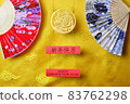 Gold tiger symbol and pair of chinese bamboo paper fans on yellow fabric with traditional chinese ornament with clouds. Chinese New Year of the Tiger 2022. Translation: happy new year 83762298