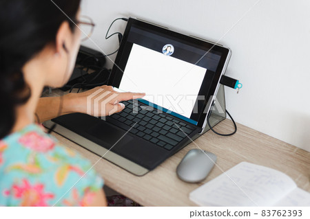 Businesswoman pointing laptop screen while making a video call in home office. Businesswoman pointing laptop screen while making a video call in home office. 83762393