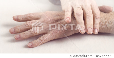The hands of an elderly well-groomed woman in a casual sweater. 83763332
