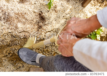 一個人用大鏟子在花園裡挖土 83763471