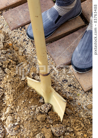 一個人用大鏟子在花園裡挖土 83763488