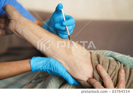 The nurse makes an injection with the vaccine to the patient at home. 83764554