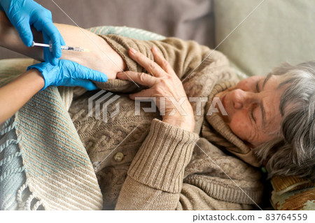 Nurse makes an injection with the vaccine to the patient at home. 83764559