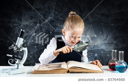 Little girl sitting at desk with magnifier 83764980