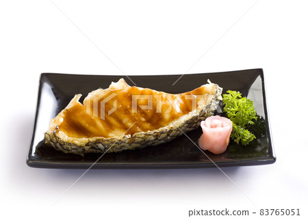 Grilled fish fillet steak with soy sauce on black dish on white background. Grilled fish fillet steak with soy sauce on black dish on white background. 83765051