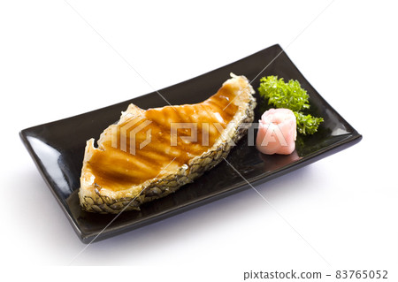 Grilled fish fillet steak with soy sauce on black dish on white background. Grilled fish fillet steak with soy sauce on black dish on white background. 83765052