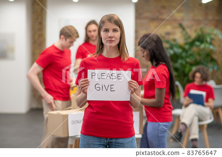 Young volunteers in red tshirts distributing donations in a sorting center Young volunteers in red tshirts distributing donations in a sorting center 83765647