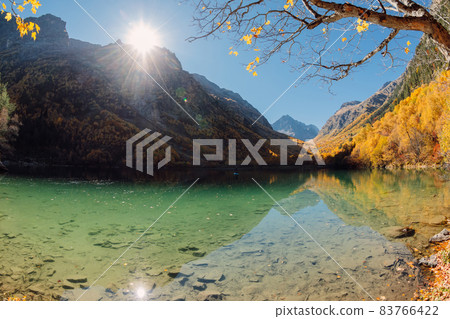 Mountain lake with crystal water and colorful autumnal trees. Mountains and lake in sunny day 83766422