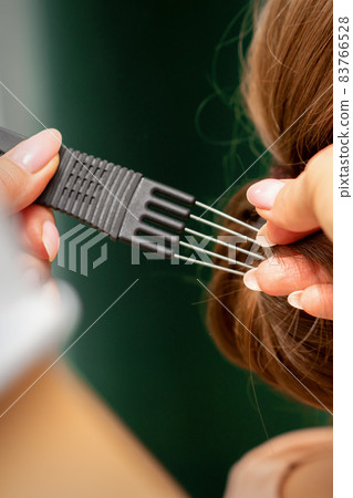 Close Up hairdresser stylist makes hairstyle for a young woman in a beauty salon. 83766528
