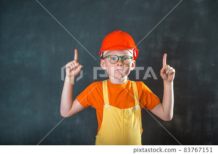 Smart kid boy in building sefaty helmet. Funny little school child in glasses pointing up on blackboard. Success, bright idea, creative ideas and innovation technology concept Smart kid boy in building sefaty helmet. Funny little school child in glasses pointing up on blackboard. Success, bright idea, creative ideas and innovation technology concept 83767151