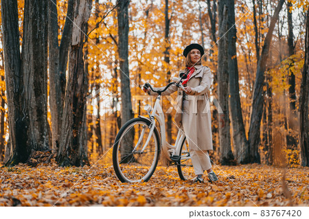 Young woman in classic trench coat with retro bicycle in yellow autumn park. Amazing scene of trendy Young woman in classic trench coat with retro bicycle in yellow autumn park. Amazing scene of trendy 83767420