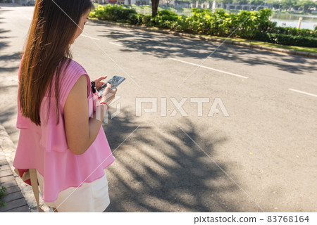 Young woman using smart phone outdoors in sunny morning 83768164