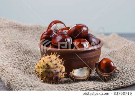 Edible chestnut kernels lie on burlap on a wooden table Edible chestnut kernels lie on burlap on a wooden table 83768719