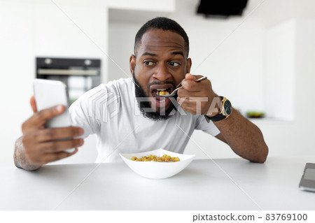 Black man rushing to work eating cereal at home Black man rushing to work eating cereal at home 83769100