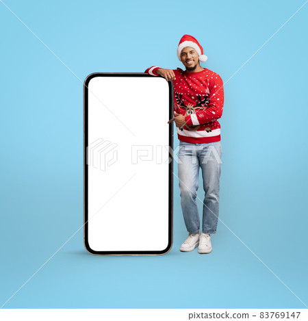 Stylish african american guy in Santa hat with big cellphone 83769147