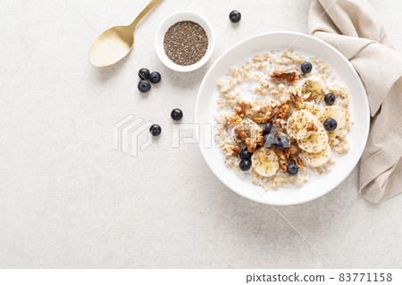 Oatmeal bowl. Oat porridge with banana, blueberry, walnut, chia seeds and almond milk for healthy breakfast or lunch. Healthy food, diet. Top view. 83771158