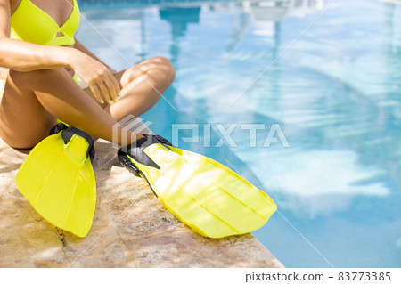 Female legs in flippers near swimming pool. Concept of summer vacation. Female legs in flippers near swimming pool. Concept of summer vacation. 83773385