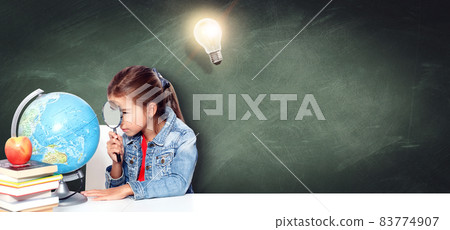 Curious little girl looking through magnifying glass on globe Curious little girl looking through magnifying glass on globe 83774907