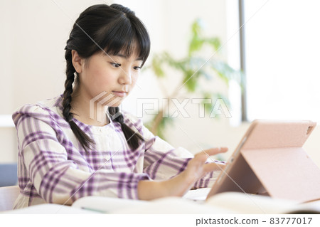 Elementary school girl studying with a tablet 83777017