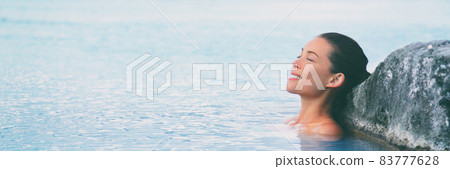 Wellness outdoor spa hot spring woman relaxing in swimming pool in Iceland. Asian tourist enjoying relaxation resort luxury vacation. 83777628