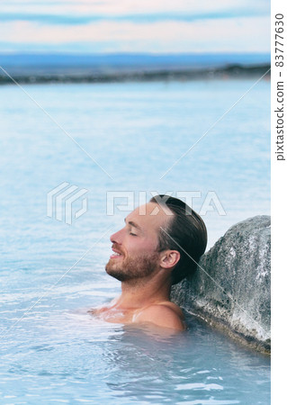 Wellness spa handsome man relaxing enjoying natural geothermal hot spring in outdoor Iceland nature. Reykjavik tourist nordic travel. 83777630