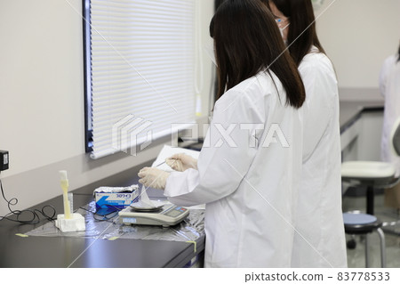 A woman weighing reagents with an electronic balance 83778533