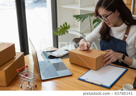Starting Small business entrepreneur SME freelance,Portrait young woman working at home office, BOX,smartphone,laptop, online, marketing, packaging, delivery, SME, e-commerce concept. Starting Small business entrepreneur SME freelance,Portrait young woman working at home office, BOX,smartphone,laptop, online, marketing, packaging, delivery, SME, e-commerce concept. 83780141
