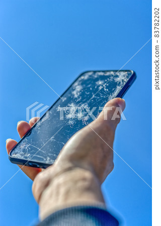 Smartphone with a broken screen after dropping Blue sky back Smartphone with a broken screen after dropping Blue sky back 83782202
