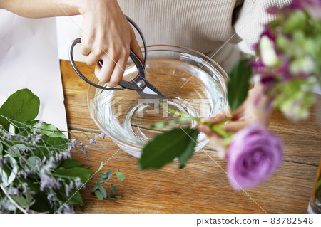 A woman's hand draining the flowers that live in the vase 83782548