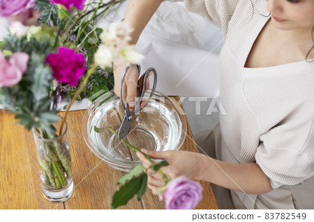 A woman's hand draining the flowers that live in the vase 83782549