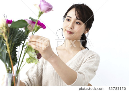 A woman who can put flowers in a vase 83783150