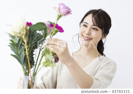 A woman who can put flowers in a vase 83783151