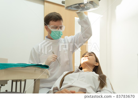 A dentist checking up Asian woman patient's teeth by using dental mouth mirror at hospital clinic. Teeth check up with dental tools. Doctor. Dentistry, medical and health. People. 83783670