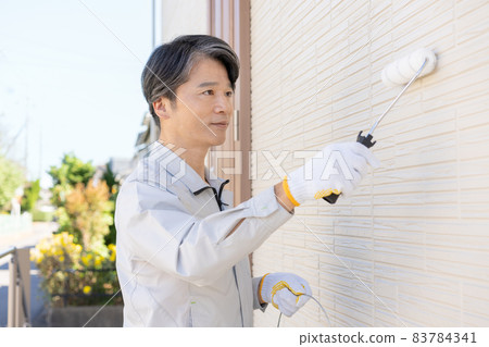 Painter painting the walls of a detached house with a roller Painter painting the walls of a detached house with a roller 83784341