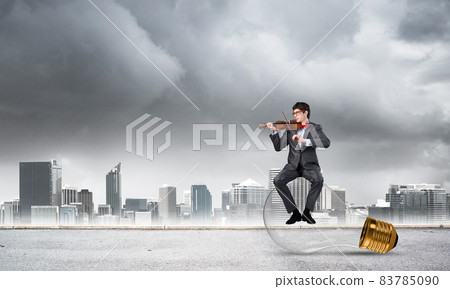 Young businessman plays the violin Young businessman plays the violin 83785090