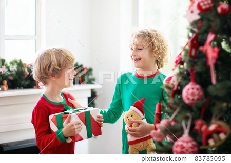 Child at Christmas tree. Kids at fireplace on Xmas 83785095