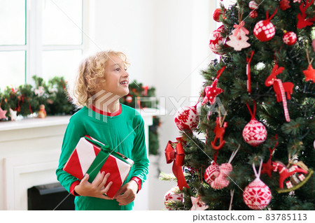 Child at Christmas tree. Kids at fireplace on Xmas Child at Christmas tree. Kids at fireplace on Xmas 83785113