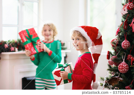 Child at Christmas tree. Kids at fireplace on Xmas Child at Christmas tree. Kids at fireplace on Xmas 83785114
