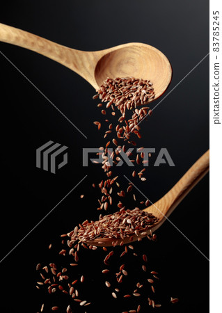 Grains of flaxseed are poured with wooden spoons. Grains of flaxseed are poured with wooden spoons. 83785245