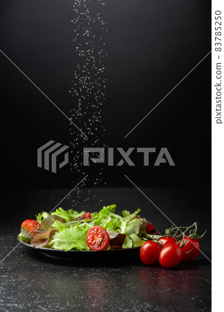 Green salad with tomatoes cherry is sprinkled with sesame seeds. 83785250