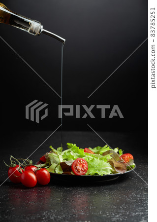 Green salad with tomatoes cherry is poured with vegetable oil. Green salad with tomatoes cherry is poured with vegetable oil. 83785251